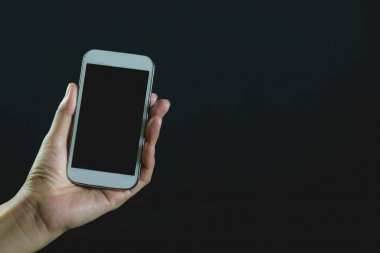 Akıllı telefon üzerinde koyu arka plan izole tutan kadın el.