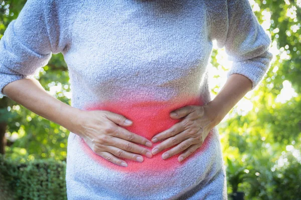 Mujer que sufre de dolor de estómago, una mujer dolor de estómago al aire libre, concepto saludable . — Foto de Stock