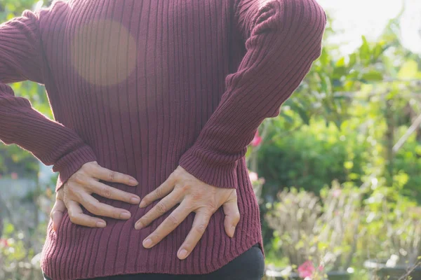 Una mujer que sufre de dolor de espalda, lesión espinal y problema de problemas musculares al aire libre . — Foto de Stock