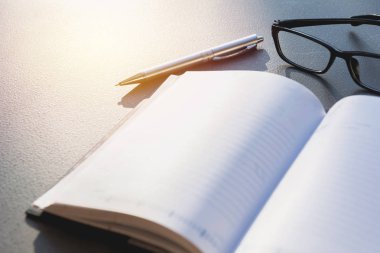 Beyaz boş defter, gözlük ve kalem tablo kopya alanı ile ders kitabı.