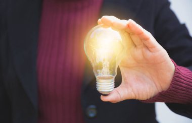 Businesswomean ampul fikir veya başarı veya güneş enerjisi için tutan eli