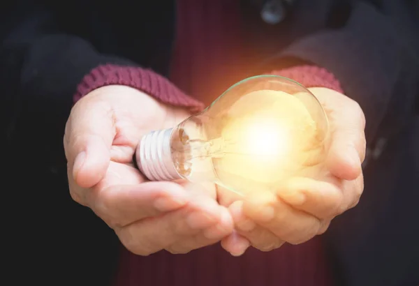 Ruka podnikatelka drží žárovku za nápad nebo úspěch nebo solární energie — Stock fotografie