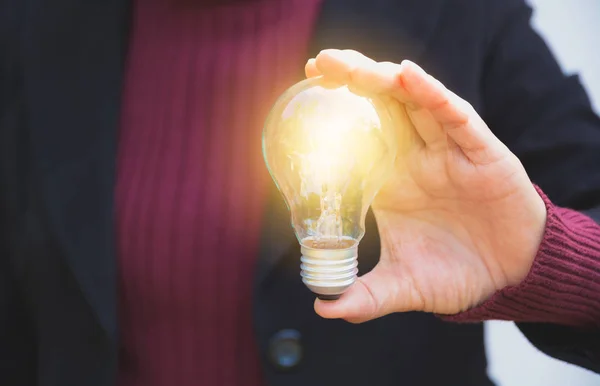 Main de femme d'affaires tenant ampoule pour l'idée ou le succès ou l'énergie solaire — Photo