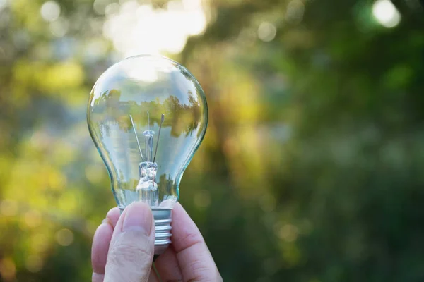 Mano de la persona que sostiene la bombilla para la idea o el éxito o el concepto de energía solar . — Foto de Stock