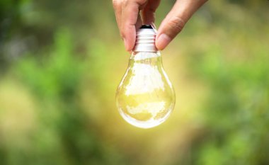 Fikir veya başarı veya güneş enerjisi kavramı için ampul tutan kişi el.