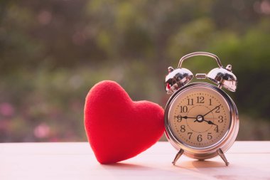 Ahşap masa Sevgililer günü konsepti için çalar saat ile kırmızı kalp.