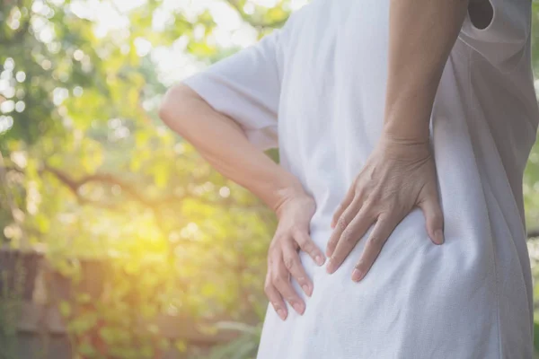 Una mujer que sufre de dolor de espalda, lesión espinal y problema de problemas musculares al aire libre . — Foto de Stock