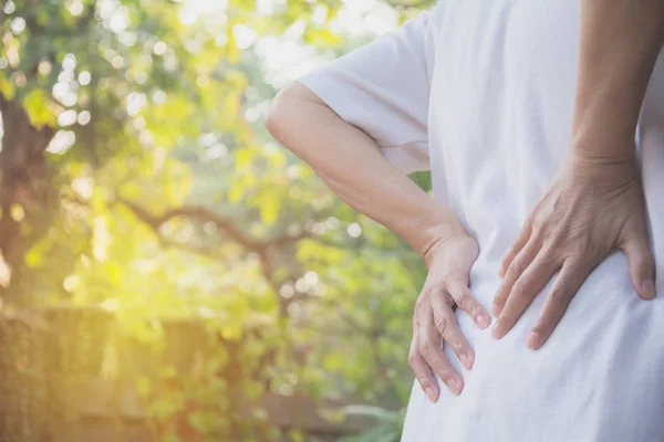 Una mujer que sufre de dolor de espalda, lesión espinal y problema de problemas musculares al aire libre . —  Fotos de Stock