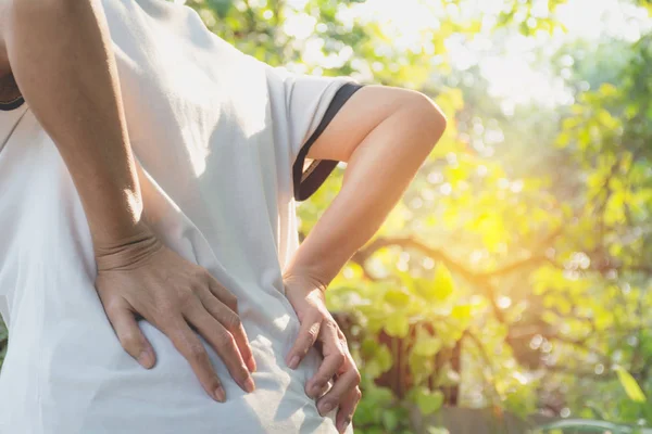 Una mujer que sufre de dolor de espalda, lesión espinal y problema de problemas musculares al aire libre . — Foto de Stock