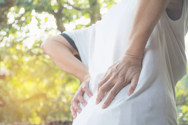 Una mujer que sufre de dolor de espalda, lesión espinal y problema de problemas musculares al aire libre . —  Fotos de Stock