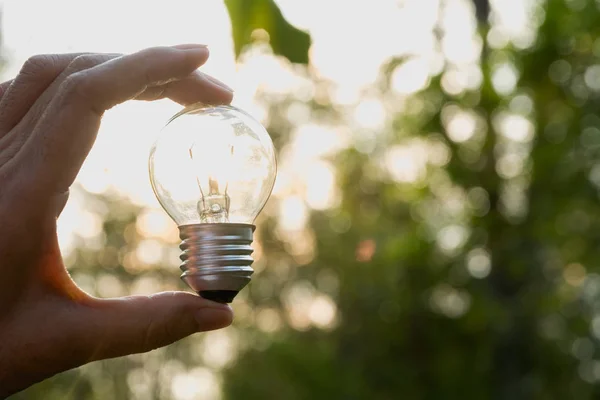 Ruka člověka drží žárovku za nápad nebo úspěch nebo solární energetické koncepce. — Stock fotografie