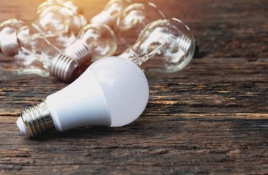 Ahşap masa arka plan üzerinde parlayan ile ampulleri. Fikir, yaratıcılık ve ampulleri kavramı ile enerji tasarrufu.