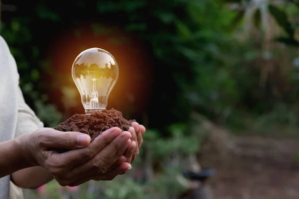 Hand einer Person mit Glühbirne für Idee oder Erfolg und Solarenergiekonzept. — Stockfoto