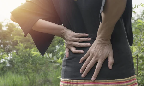 Una mujer que sufre de dolor de espalda, lesión espinal y problema de problemas musculares al aire libre . —  Fotos de Stock