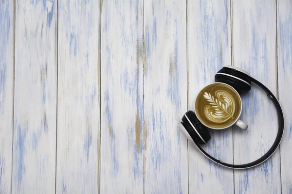 Una taza de café con auriculares en la mesa de madera. Vista superior del café latte arte con espacio para copias. Concepto de bebida y arte . — Foto de Stock