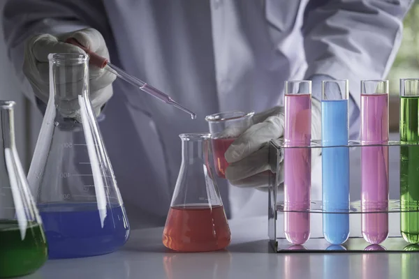 Исследователь со стеклянными лабораторными химическими пробирками с жидкостью — стоковое фото