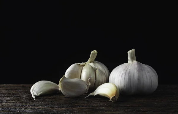 Aglio bianco fresco su tavolo di legno con sfondo nero. Cibo a — Foto Stock