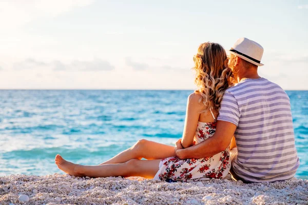 Junges verliebtes Paar sitzt am Strand — Stockfoto