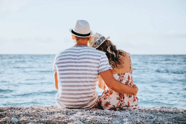 Jong paar in liefde zitten op het strand — Stockfoto