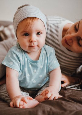 Sevimli küçük gülümseyen bebek kız annesiyle odasında oynuyor.