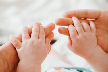 Uyku sırasında annesinin elini tutarak şirin bebek. Mutlu aile kavramı.