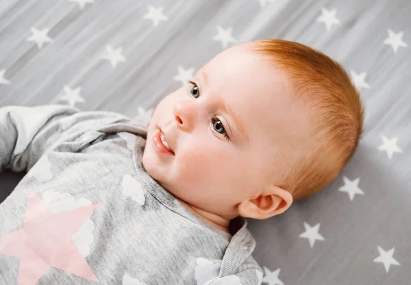 Gelukkig lachende babymeisje met haar speelgoed op het bed. — Stockfoto