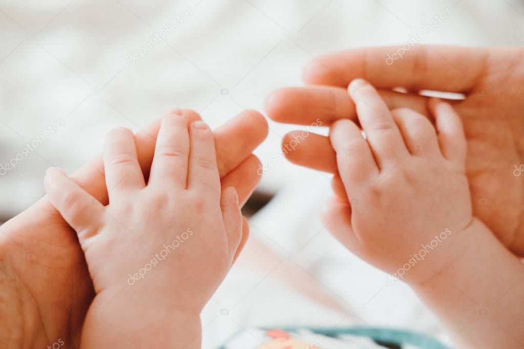 Cute newborn baby holding mother's hand while sleeping. Happy Family concept.