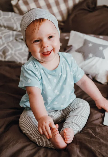 Schattig klein happy babymeisje speelt zittend op een bed in een kamer. Gelukkige familie plezier. — Stockfoto