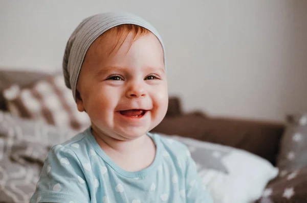 Söt liten glad baby flicka spelar sitter på en säng i ett rum. Lycklig familj ha kul. — Stockfoto