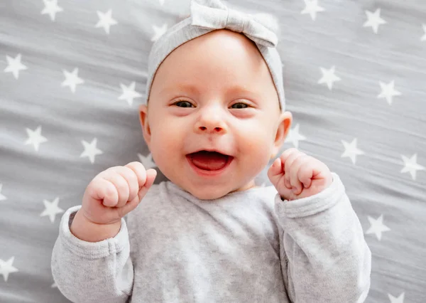 Happy laughing baby girl on her bed.