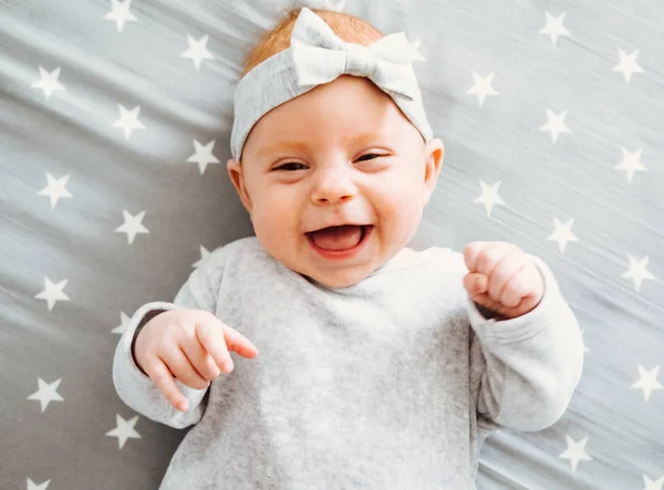 Gelukkig lachende babymeisje op haar bed. — Stockfoto