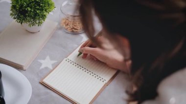 Young woman makes notes in her diary.