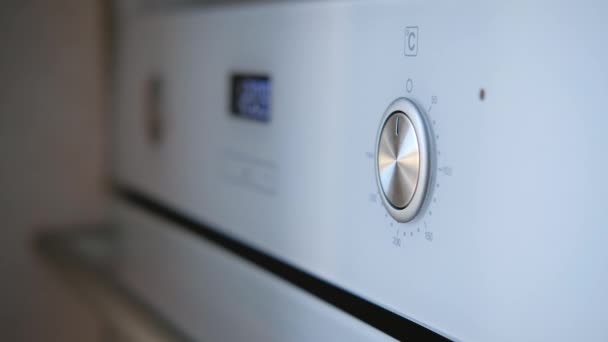 Gros plan de la main féminine tourne le commutateur de four définit la température 