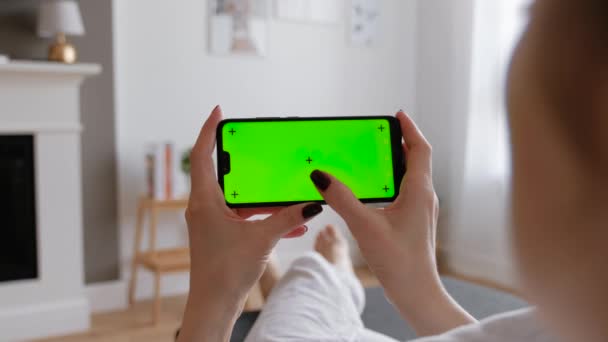 Mladá žena pomocí chytrého telefonu sedí na pohovce doma. — Stock video