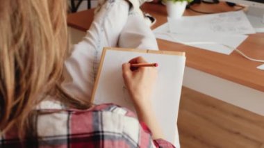 Beyaz kağıt üzerinde çizim yapan kadın ressam, ev ofisinden çalışıyor.