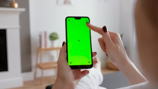 Evde koltukta oturan akıllı telefonu kullanan genç bir kadın.. — Stok video
