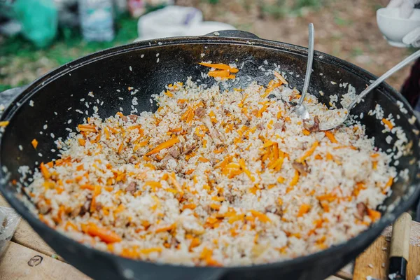 Uzbekiska pilaff i kitteln. Pilau i en kock på en picknick. — Stockfoto