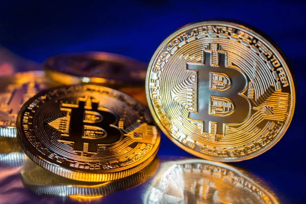 Foto Golden Bitcoins nuevo dinero virtual Primer plano sobre un fondo azul . — Foto de Stock