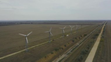 Aerial view old wind turbines spinning in filed with dirt road