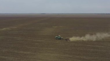Aerial view farmer cultivates land on a tractor.