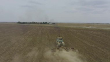 Aerial view tractor plows the field. Establishing shot