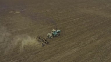 Aerial view tractor cultivating the land. dust behind the machine