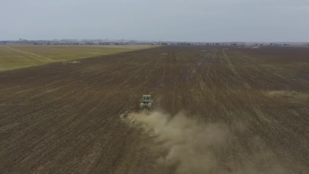 Vue aérienne tracteur monte sur le terrain, derrière lui vole épaisse poussière 