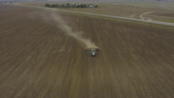Vue aérienne agriculteur cultive des terres sur un tracteur. La poussière volante derrière la machine .