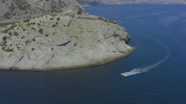 Kırım 'daki kayalık adanın yakınlarında denizde kükreyen hava manzaralı tekne.