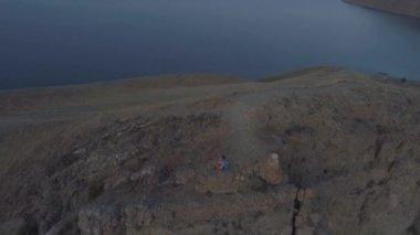 Uçurumun kenarındaki dağlarda oturan hava manzaralı kız.