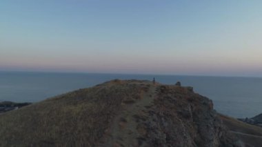 Havadan bakan kız dağın zirvesine çıktıktan sonra ellerini kaldırıyor.