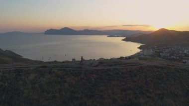 Gün batımında taşın üstünde uçan kız.