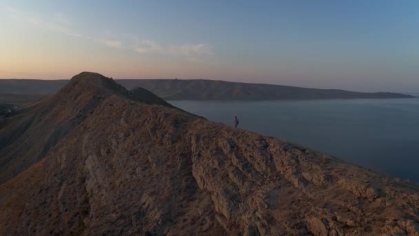 Vue aérienne d'une fille avec un sac à dos se lève sur une crête de montagne .