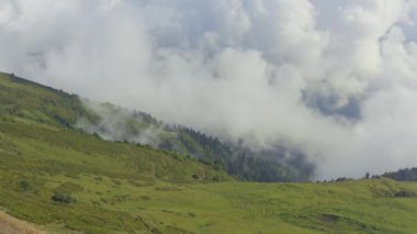 Gökyüzü manzaralı, yükselen bulutlu yeşil dağ manzarası.